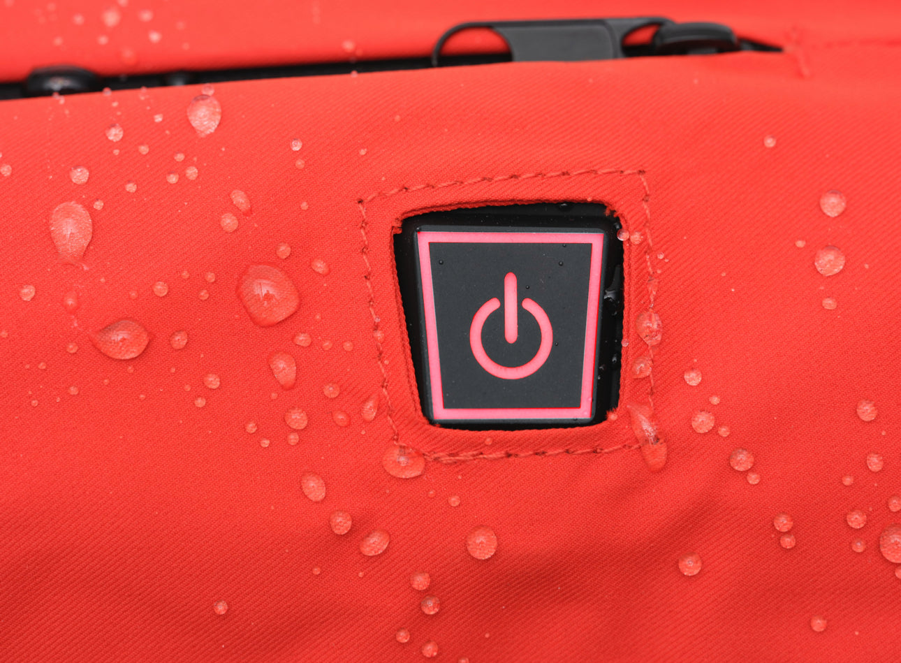 close up of the heated hand warmers on/off button. showcasing the water resistant shell