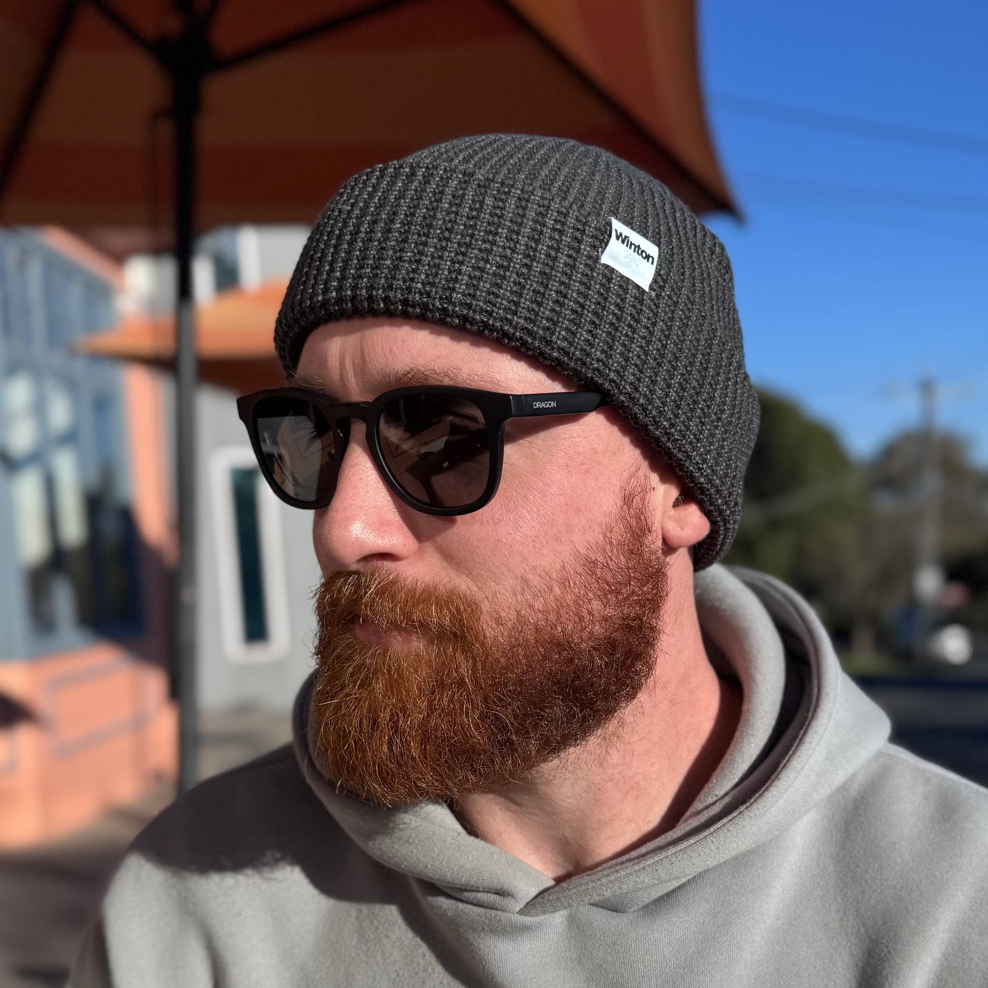Man wearing a ultra soft warm beanie and sunglasses outdoors with a coffee shop background